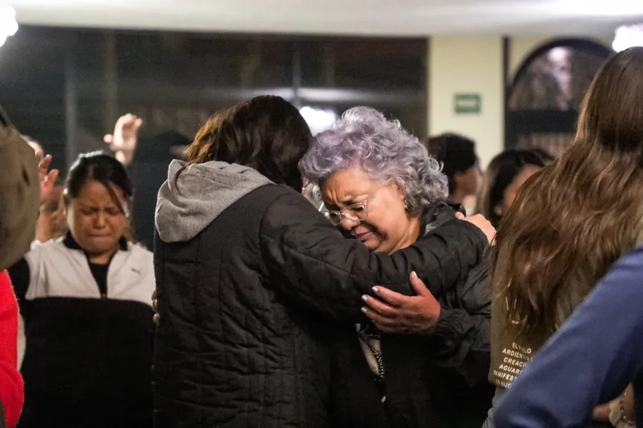 Dos mujeres se abrazan durante la oración