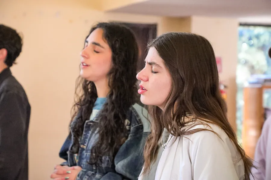 Dos jóvenes alaban con los ojos cerrados