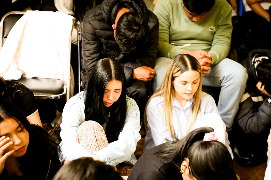 Jóvenes oran sentados en el piso del salón