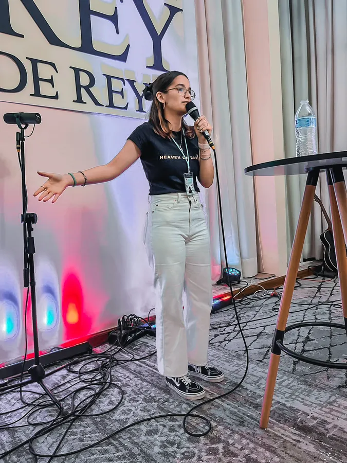 Una joven predica frente al letrero de Rey de Reyes