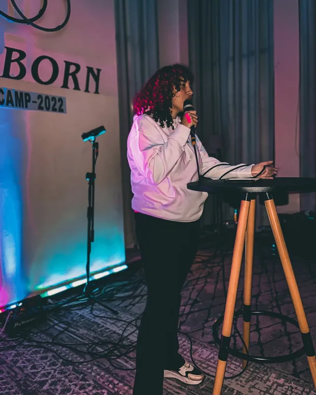 Predicadora junto al letrero de REBORN Camp 2022