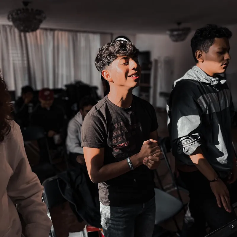 Joven alaba con las manos juntas y los ojos cerrados