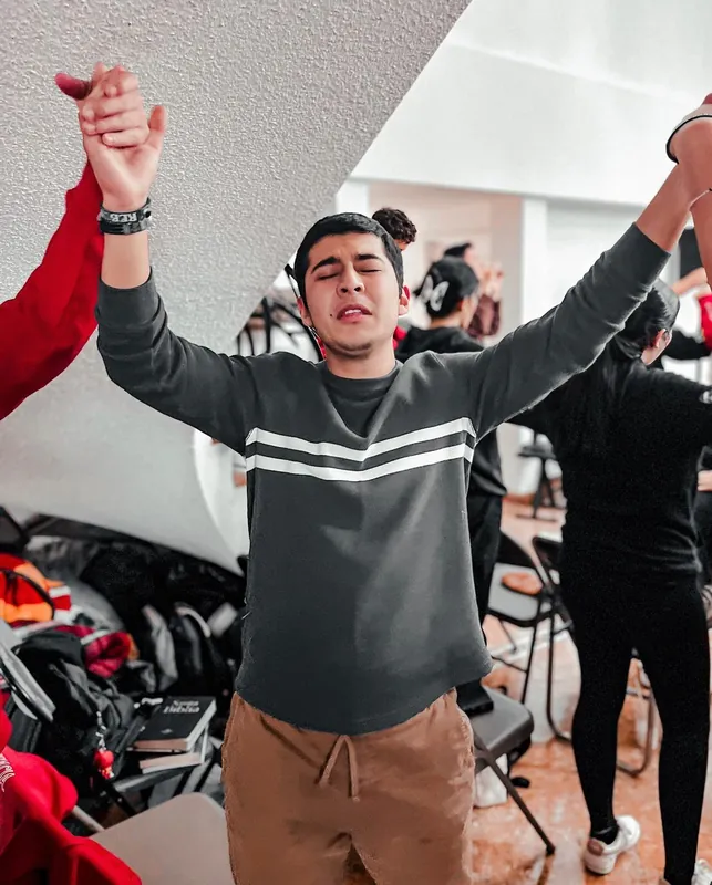 Joven levanta los brazos durante la alabanza
