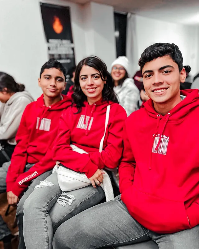 Tres jóvenes con sudaderas rojas sonríen sentados