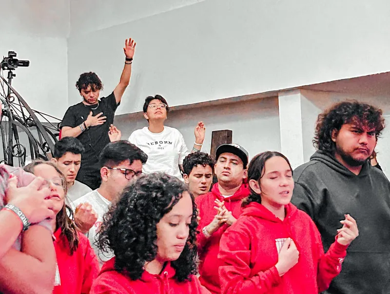 Jóvenes con sudaderas rojas alaban con los ojos cerrados