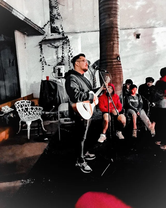 De noche, un invitado toca la guitarra y canta en el patio