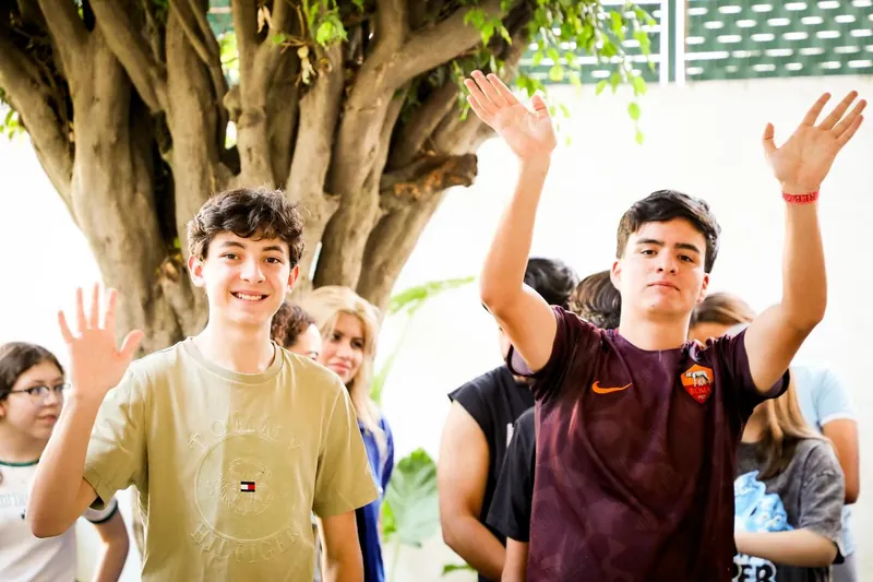 Dos jóvenes saludan con la mano durante las dinámicas