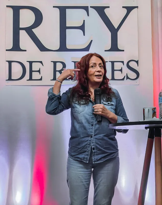 Predicadora con chamarra de mezclilla habla con micrófono