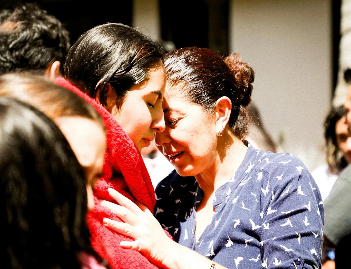 Una señora y una joven se abrazan después del bautizo