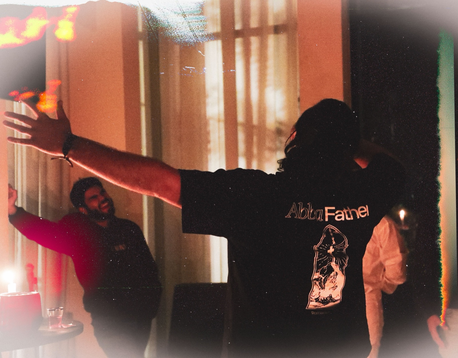 Josué, de espaldas, con la sudadera «Abba Father» y los brazos abiertos, en la noche de alabanza de REBORN 2026