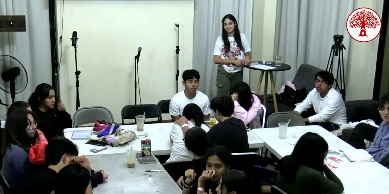 Jóvenes reunidos alrededor de mesas en una actividad en grupos durante REBORN Camp 2025.