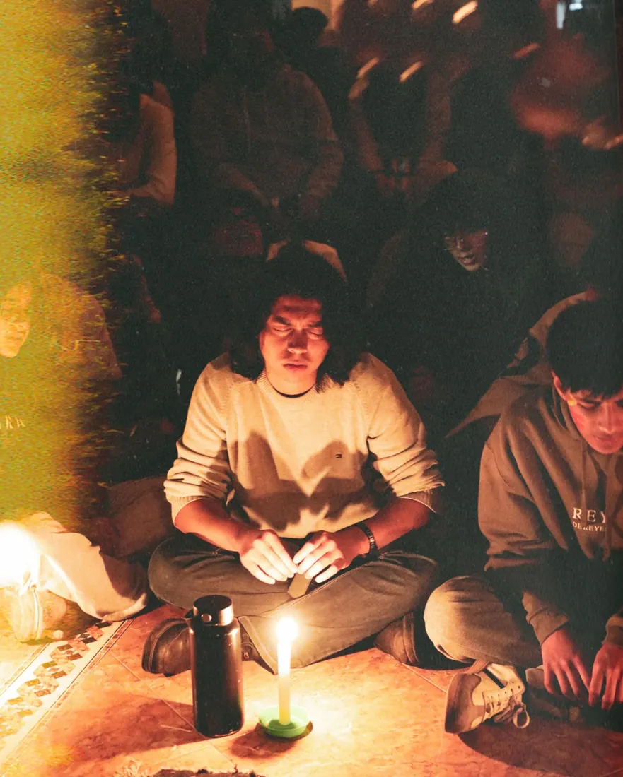 Un joven en oración frente a una vela, en la última noche de REBORN 2026.